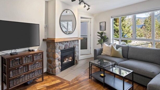 A living room with a stone fireplace, a flat-screen TV, a sofa, and a coffee table.