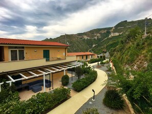 Un quartier résidentiel situé sur une colline, avec des maisons à étages, un sentier sinueux et une vue sur les montagnes en arrière-plan.
