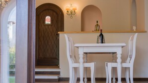 A white dining table with four chairs in a room with a wooden door and a light-colored wall.