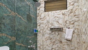 A bathroom with a marble wall, a sink, a shower, and a towel rack. - Hotel Lord Krishna Dham (Dwarka)