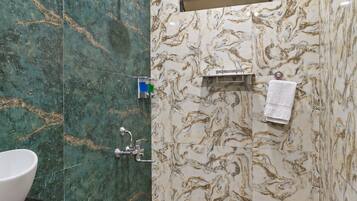 A bathroom with a marble wall, a sink, a shower, and a towel rack.