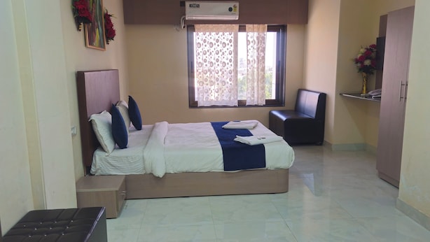 A hotel room with a bed, a desk, a chair, and an air conditioning unit. - Hotel Lord Krishna Dham (Dwarka)