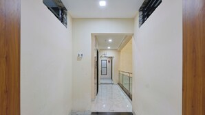 A corridor with a marble floor, wooden walls, and a glass railing. - Hotel Lord Krishna Dham (Dwarka)
