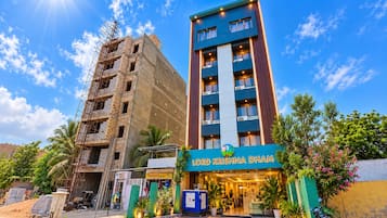 Un hotel llamado 'Lord Krishna Dam' con una fachada moderna, una entrada bien conservada y un cielo despejado.