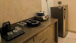 Una cocina con encimera de mármol, estufa, refrigerador y una pequeña planta en maceta.