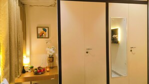 Habitación de hotel con tocador de madera, espejo, cuadro enmarcado, florero con flores y frutero.