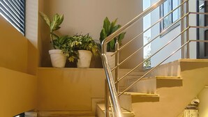 Una escalera con barandilla de metal, escalones de madera y plantas en macetas en el descansillo.