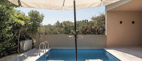 Una piscina con sillas de descanso y una sombrilla.