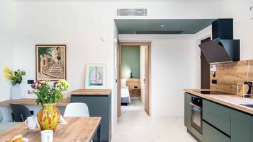 Een moderne keuken met een eethoek, met een houten tafel, stoelen, een vaas met bloemen en kunstwerken aan de muren.