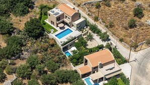 Una villa moderna con dos piscinas, un jardín ajardinado y un camino de piedra.