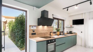 Una cocina moderna con una isla grande, horno empotrado y televisor de pantalla plana montado en la pared.