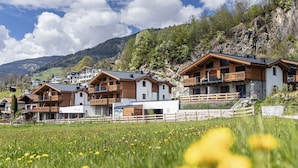 A row of wooden chalets with balconies, set against a mountainous backdrop. - Superior Ferienhaus # 4A mit Sauna (Uttendorf)