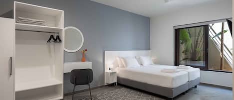 Un dormitorio moderno con cama, armario, escritorio y un ventanal grande.