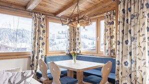 A cozy room with a wooden ceiling, a round table with blue cushioned chairs, and a bench seating area.