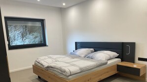 A modern bedroom with a bed, nightstands, and a window with a view of a rocky landscape. - Vacation apartment Am Kreuzberg Apartment No. 3 (Nordrhein-Westfalen - Schleiden)