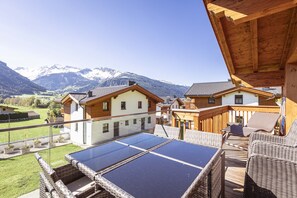 A wooden deck with solar panels, wicker furniture, and a mountain view. - Superior Ferienhaus # 5A mit Sauna (Uttendorf)