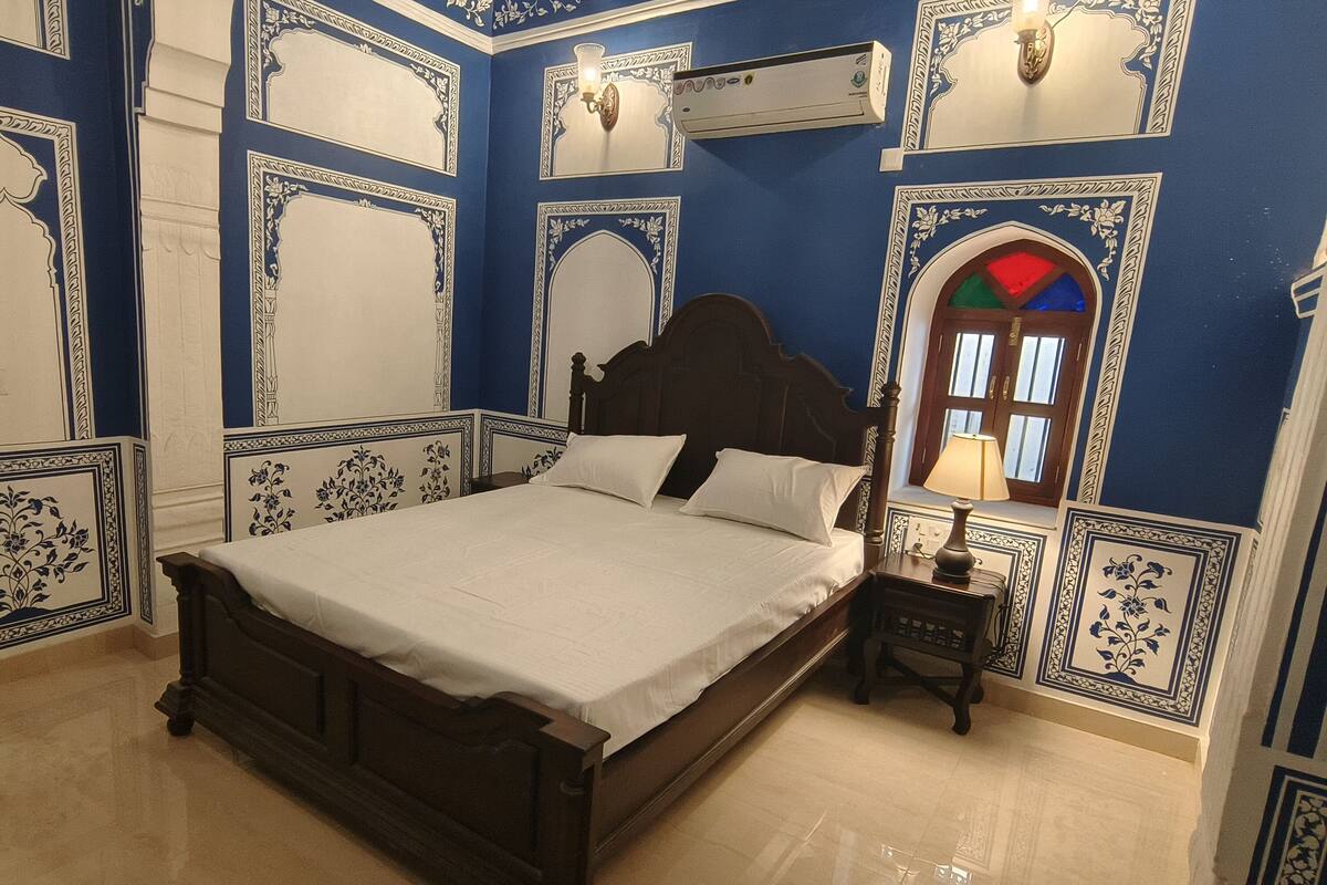 A bedroom with a large bed, a nightstand, and a window with a view.