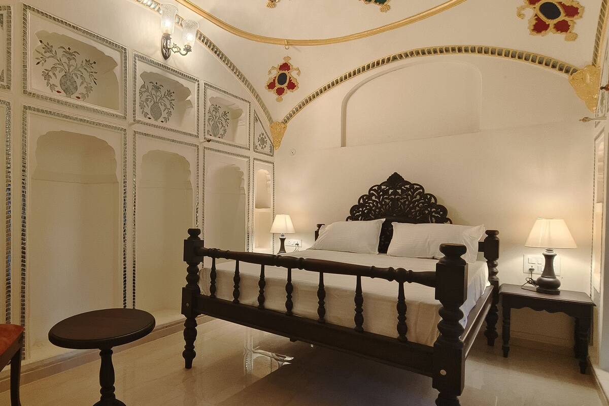 A bedroom with a bed, a chair, a nightstand, and decorative wall panels.