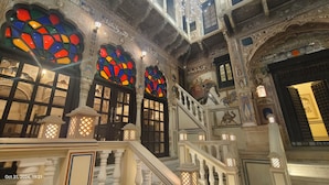 A grand staircase with ornate railings and a series of stained glass windows. - HOTEL MANDAWA VILAS (Jhunjhunu)