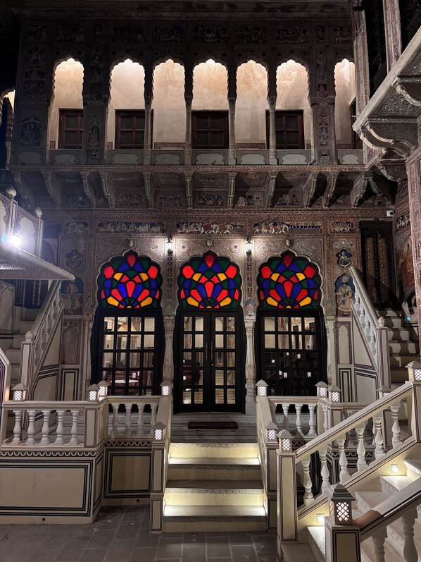 Un'imponente ingresso caratterizzato da archi decorati e una scalinata che conduce ai piani superiori.