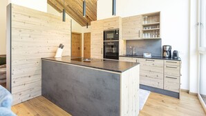 A modern kitchen with wooden cabinetry, a central island, and built-in appliances.