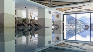Un espace intérieur moderne doté d’un sol en verre, de fauteuils confortables et d’une grande fenêtre offrant une vue sur les montagnes.