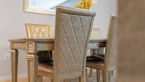 Un coin repas avec une table et des chaises, un miroir au mur et un vase contenant des fleurs séchées.