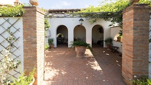 A courtyard with brick walls, arches, potted plants, and a pergola. - Stunning private villa for 7 people with A/C, private pool, WIFI, patio and panoramic view (Cortona)