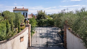 A gated entrance to a property with a traditional building, surrounded by greenery and a clear sky. - Stunning private villa for 7 people with A/C, private pool, WIFI, patio and panoramic view (Cortona)