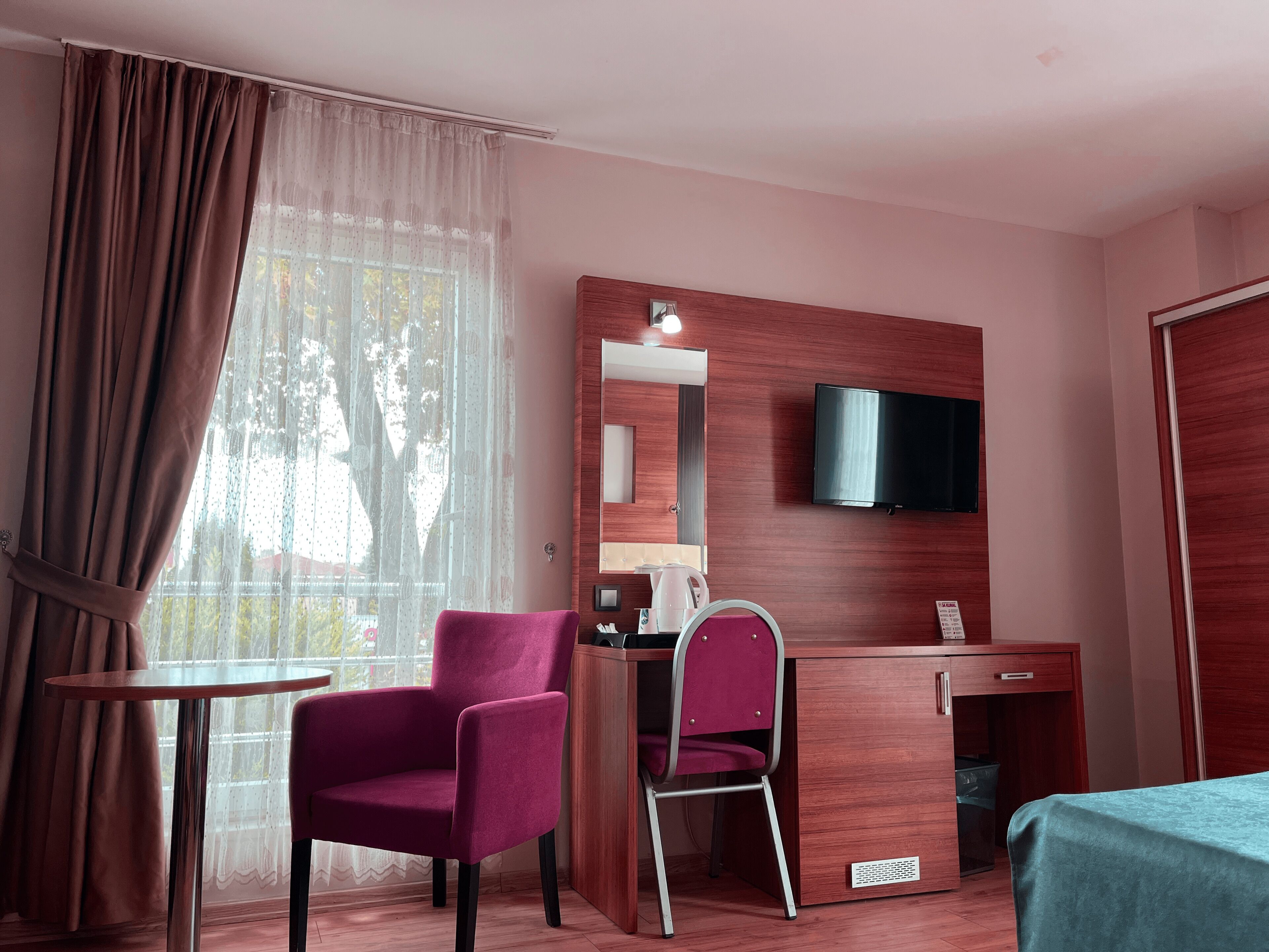 A hotel room with a desk, chair, TV, and a bed.