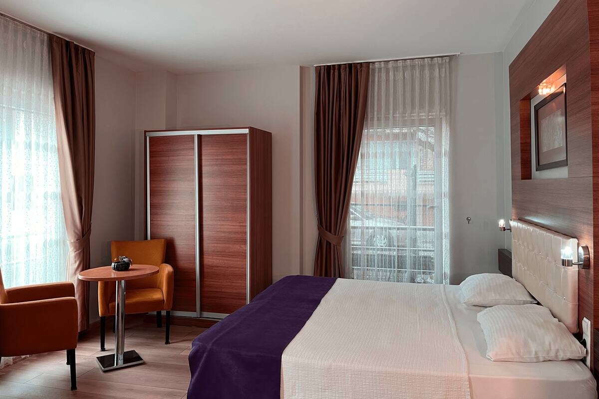 Une chambre d’hôtel avec un lit, une chaise, une petite table et une armoire.
