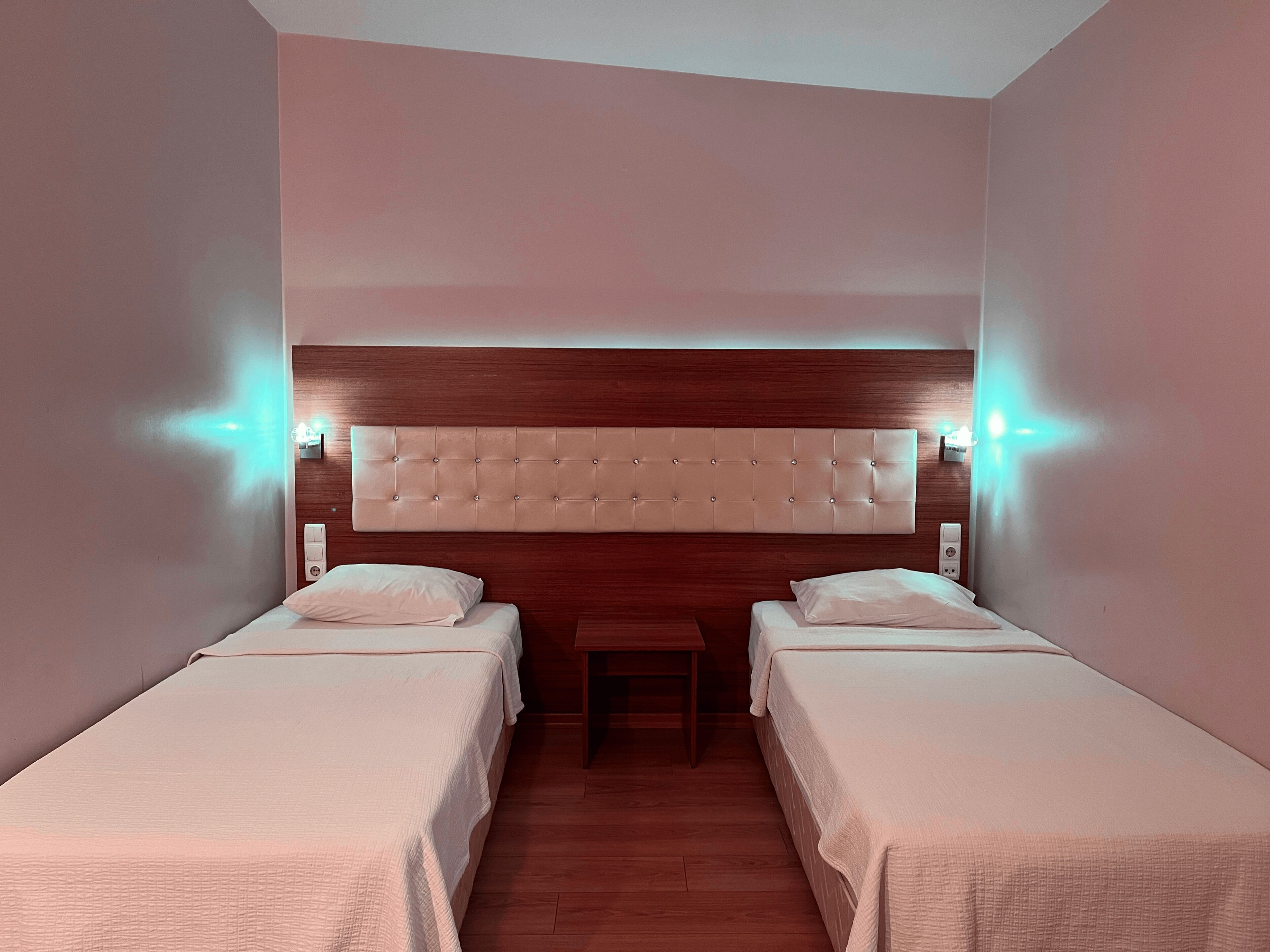 Habitación de hotel con dos camas, cabecero de madera e iluminación empotrada.