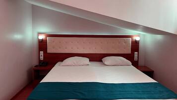 A hotel room with a bed, bedside tables, and a headboard with wall-mounted lights.