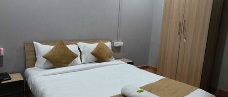 A neatly made bed with a white and brown bedspread, two pillows, and a rolled towel.