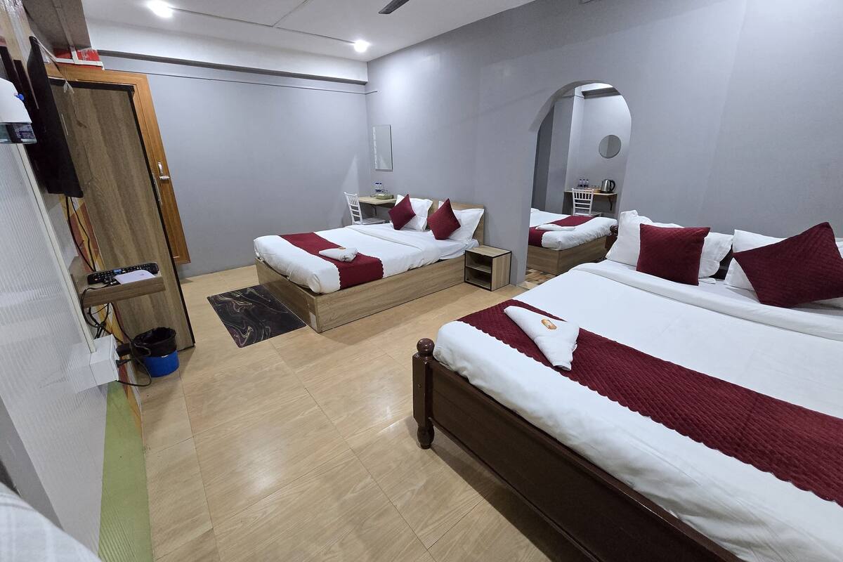 Une chambre d’hôtel avec deux lits simples, une armoire en bois, un bureau et un miroir.