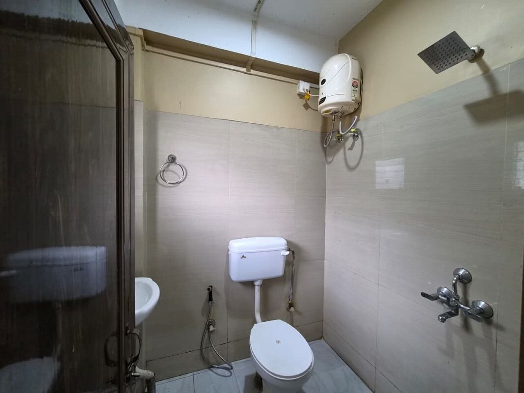 A small bathroom with a toilet, a sink, and a showerhead.