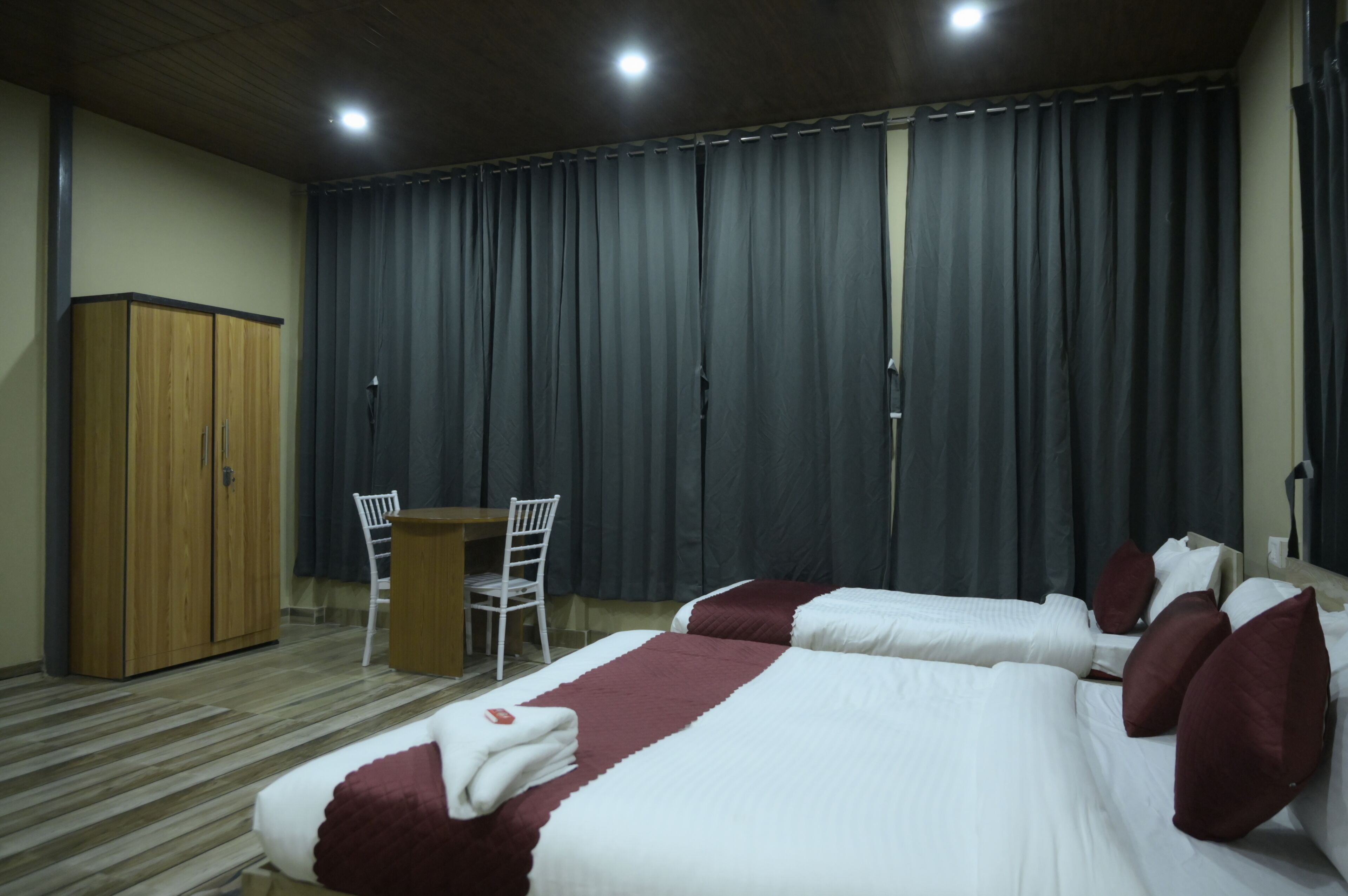 Une chambre d’hôtel avec deux lits, une armoire en bois, un bureau et une chaise.