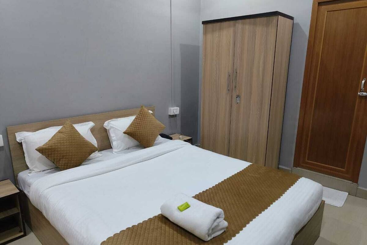 Un lit bien fait, agrémenté d’une touche de couleur marron, une armoire en bois et un meuble en bois dans une chambre d’hôtel.