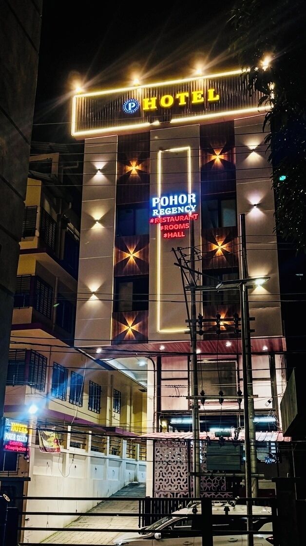 Un hotel con un llamativo letrero de neón, una franja de luz vertical y un gran logotipo iluminado.