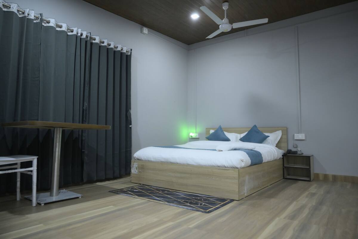 Une chambre à coucher avec un lit en bois, une table de chevet, un bureau et un ventilateur de plafond.