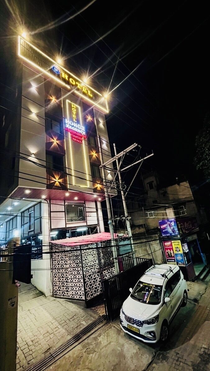 A hotel with a prominent sign, a gated entrance, and a parked car.