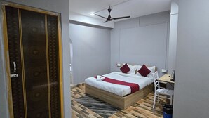 A bedroom with a bed, a desk, a chair, a wardrobe, and a ceiling fan. - Hotel Pohor Regency Near Kamakhya Foot Bridge (Guwahati)