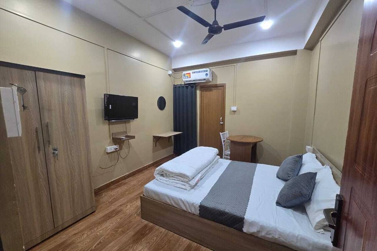 Une chambre à coucher comprenant un lit, une armoire, un téléviseur et un ventilateur de plafond.
