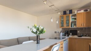 A modern kitchen with wooden cabinets, a built-in oven, and a coffee maker.