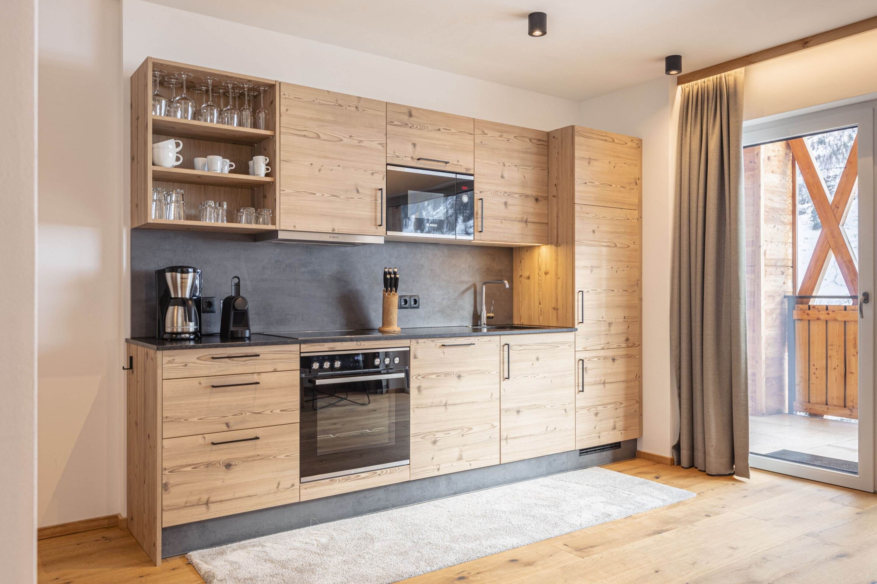 Eine moderne Küche mit Holzschränken, einem eingebauten Ofen und einer Kaffeemaschine.