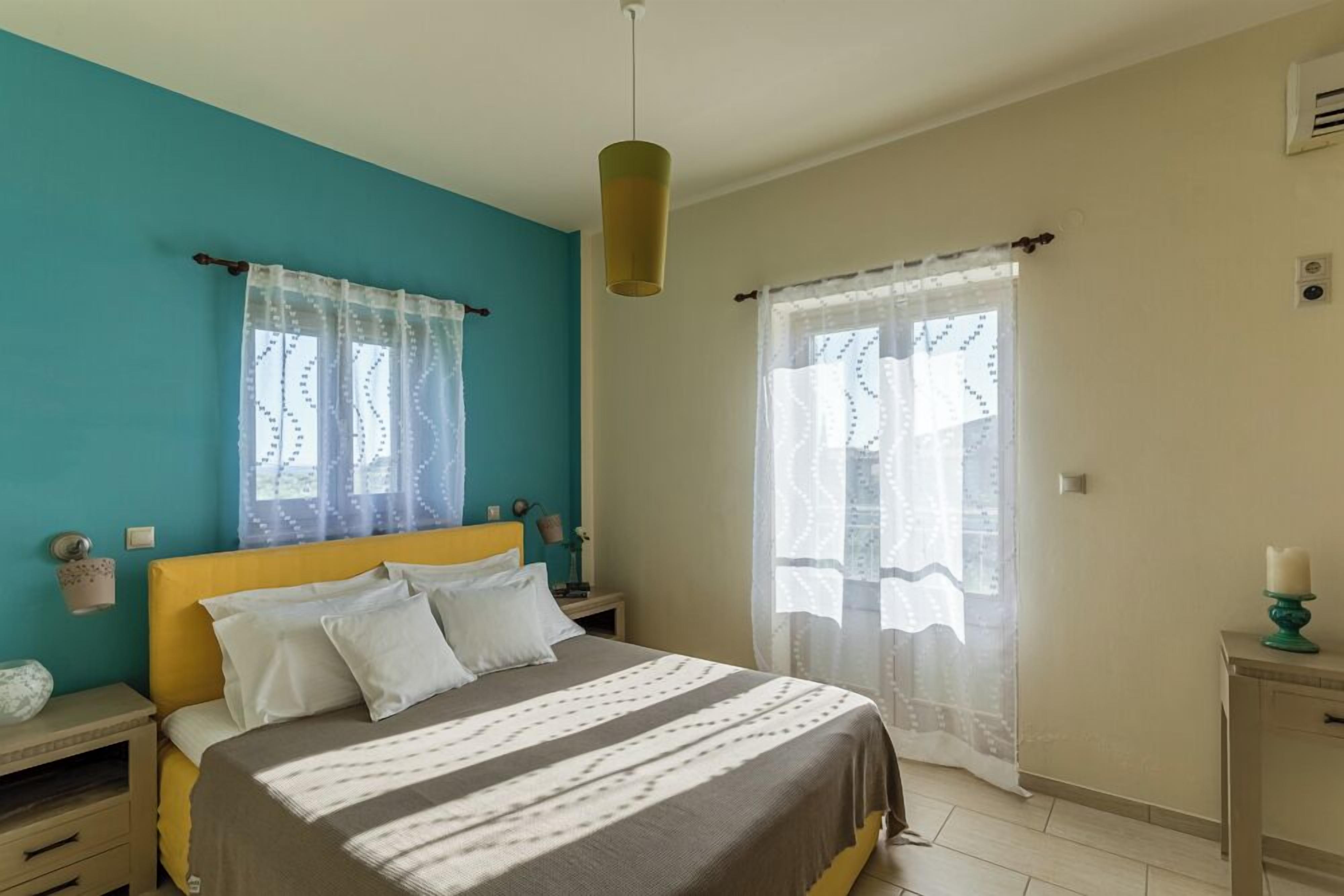 A bedroom with a bed, nightstands, a lamp, and a window with curtains.