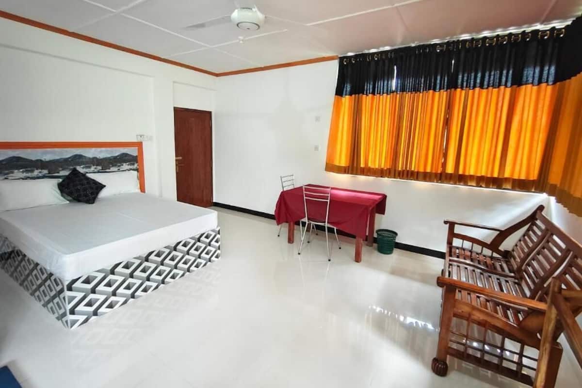 A hotel room with a bed, a table, and a chair.