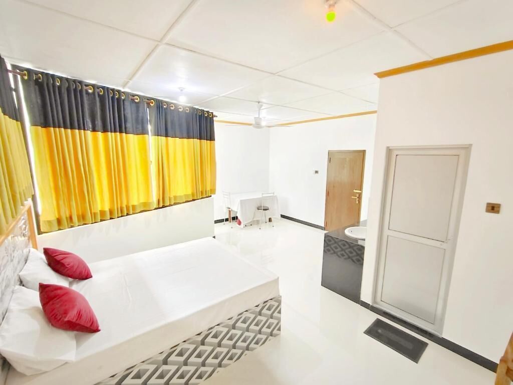 Een hotelkamer met een bed, een tafeltje, een stoel, een spiegel en een deur.