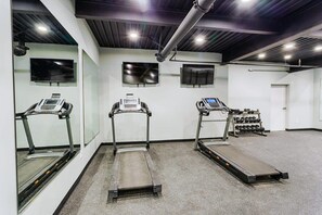 Ein Fitnessraum mit Laufbändern, einem Ergometer und einem Gewichtständer.