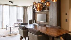 Un comedor moderno con una amplia mesa de madera, seis sillas y tres lámparas colgantes de cobre.